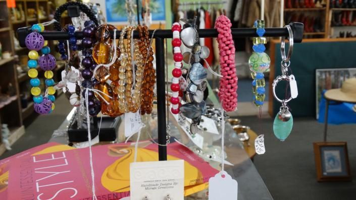 Colorful beaded bracelets and charm keychains displayed on stands at a market stall