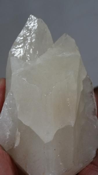 Translucent white crystal cluster held upright in a hand