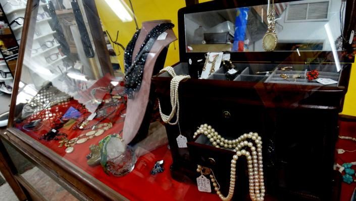 Jewelry display with pearl necklaces, high heels, and red decorative items in a shop window