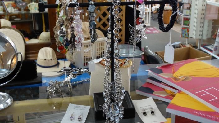 Jewelry display with sparkling necklaces and bracelets on a shop counter, with colorful papers in the background