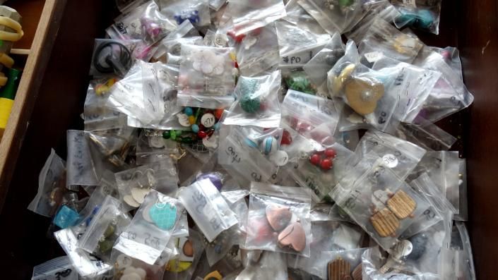 Assorted small items in clear plastic bags piled in a wooden drawer