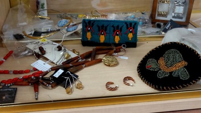 Assorted jewelry and trinkets on a table, with a black beaded purse and colorful decorative box.