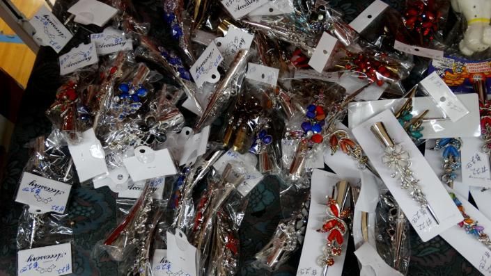 Scattered packaged earrings and jewelry on a tabletop, mostly silver, red, and black accents.