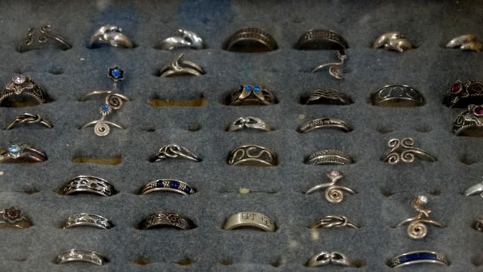 Assorted rings and jewelry arranged in rows on a dark display tray.
