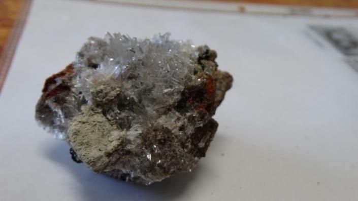 Small rough gray-and-brown mineral rock with a sparkly crystalline surface on a white background