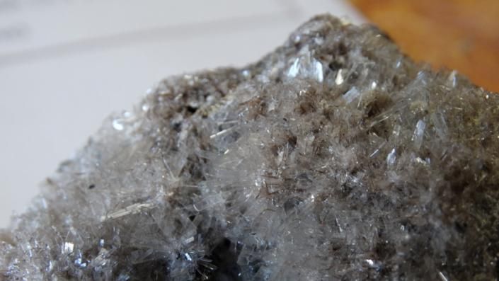 Close-up of a rough, shiny gray mineral or rock with sparkling crystals