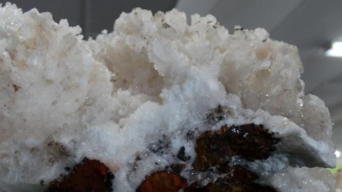 Close-up of white crystalline snow or ice on dark reddish rocks