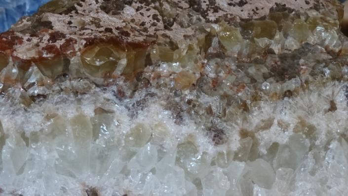 Close-up of a crystalline rock surface with white, brown, and translucent mineral layers