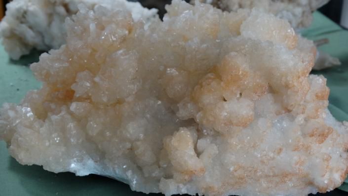 White crystalline rock or mineral clusters with pale orange tint on a dark background