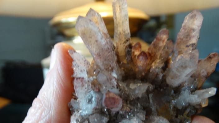 A hand holding a cluster of translucent brown and white crystals indoors