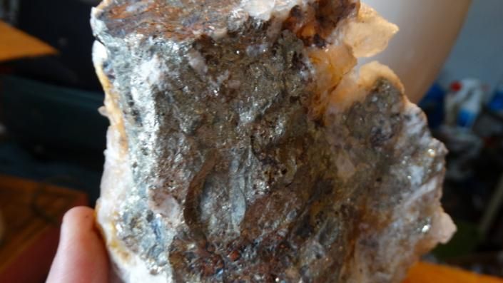 Close-up of a rough brown and white mineral rock held in a hand