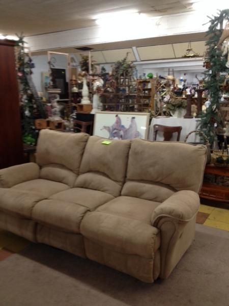 Beige loveseat in a furniture store showroom with holiday decorations in the background
