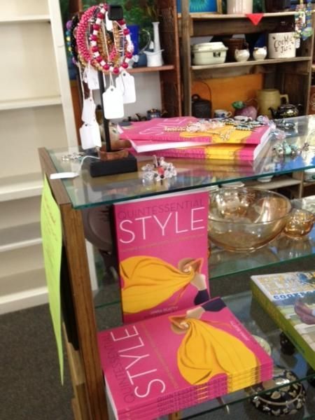 Pink “STYLE” books and jewelry on a glass display shelf in a store