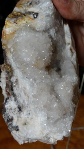 Hand holding a white crystalline rock with rough, translucent texture