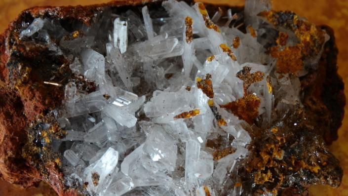White crystalline mineral cluster on a rusty brown rock surface