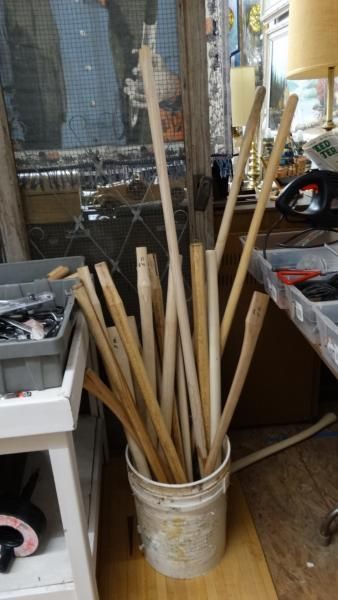 Bucket of long wooden rods and poles standing upright in a workshop corner