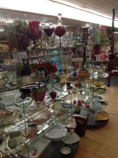 Glass shelves filled with assorted decorative glassware and bowls in a store display.