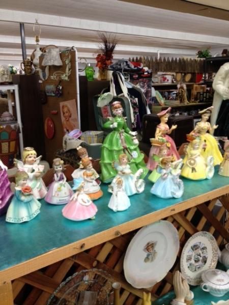 Display of colorful ceramic figurines and dolls on a turquoise table in a shop