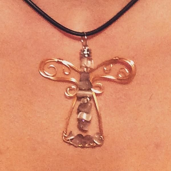 Metal angel pendant on a black cord necklace against skin.