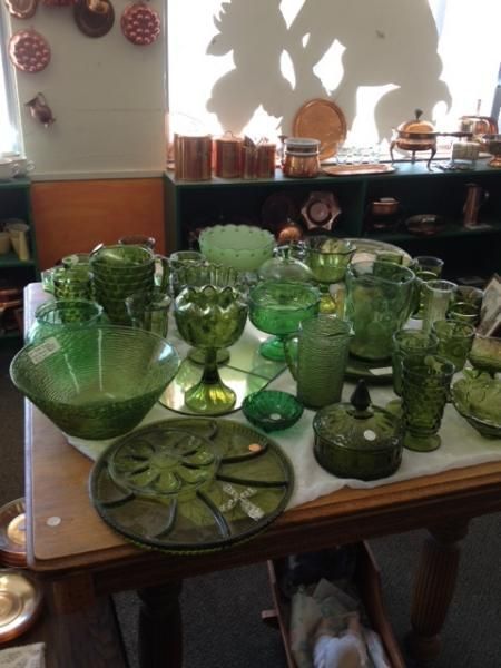 Assorted green glassware and bowls arranged on a table in a sunlit room