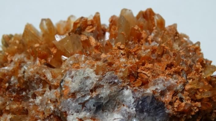 Close-up of orange-brown crystal clusters on a gray rock surface