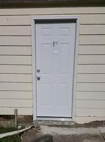 A white door is on the side of a house.