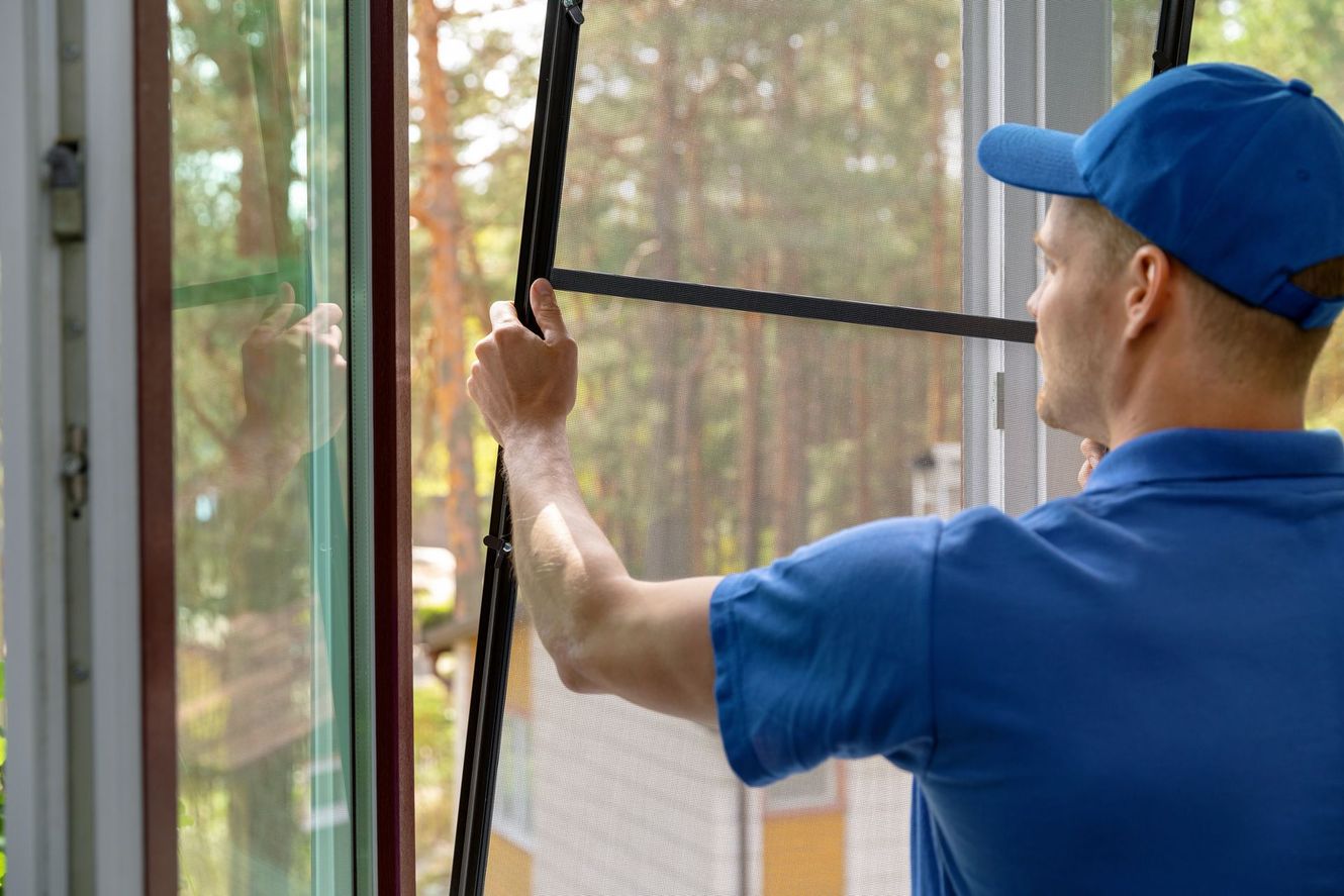 A man is installing a mosquito screen on a window.