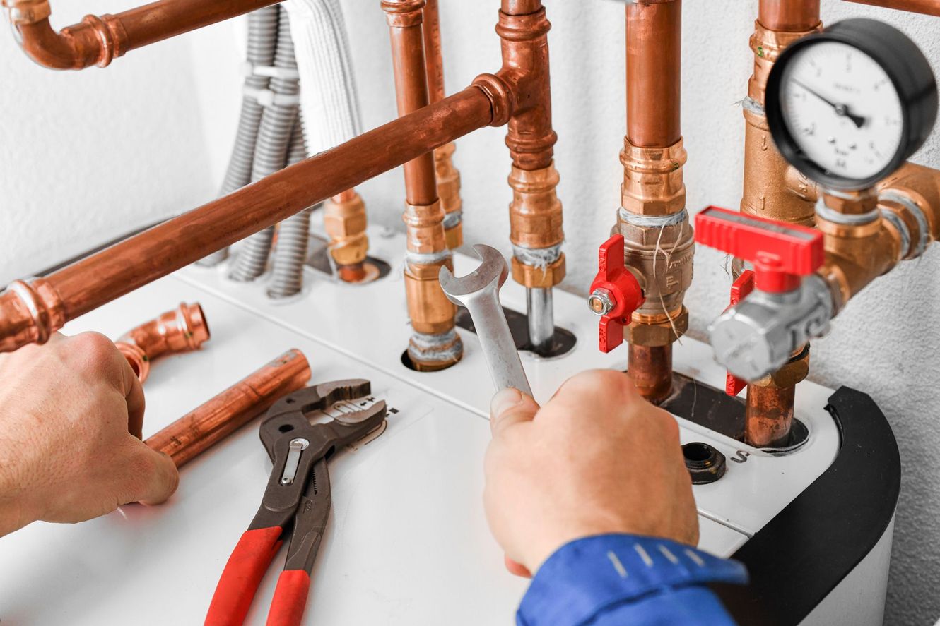 A plumber is fixing a water heater with a wrench.