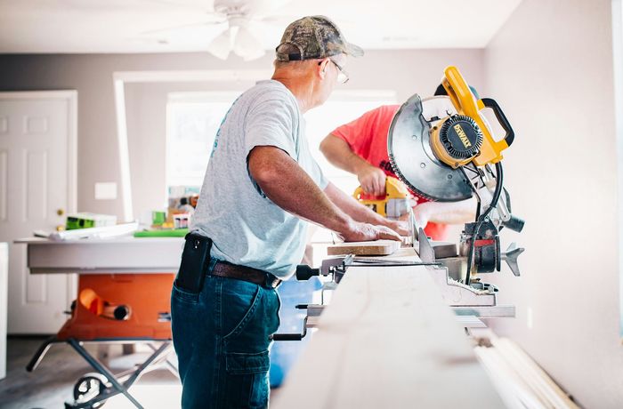 Two men are working on a circular saw in a room.
