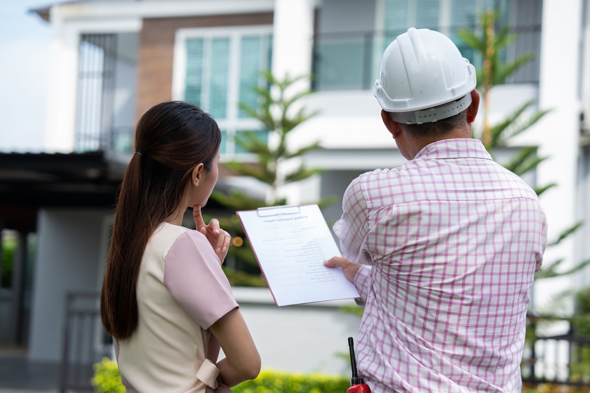 A man and a woman are standing in front of a house.