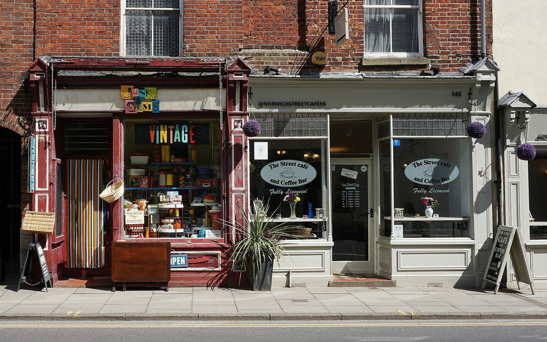 Two vintage shops with display windows on a brick building facade.