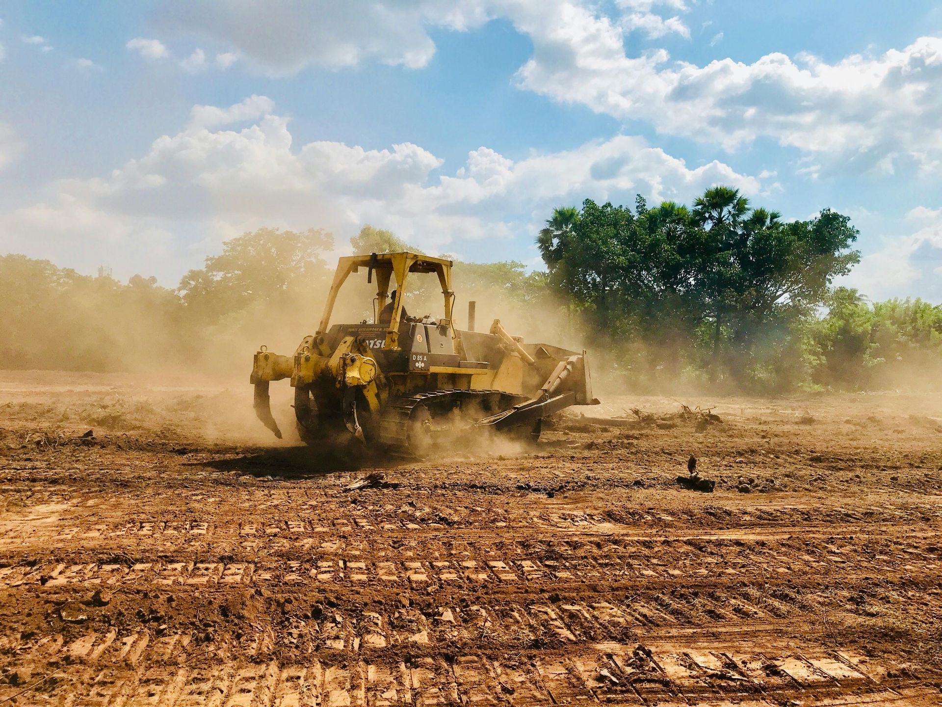 An orange excavator demolishes a teal-painted building in a snowy environment. Debris litters the ground.
