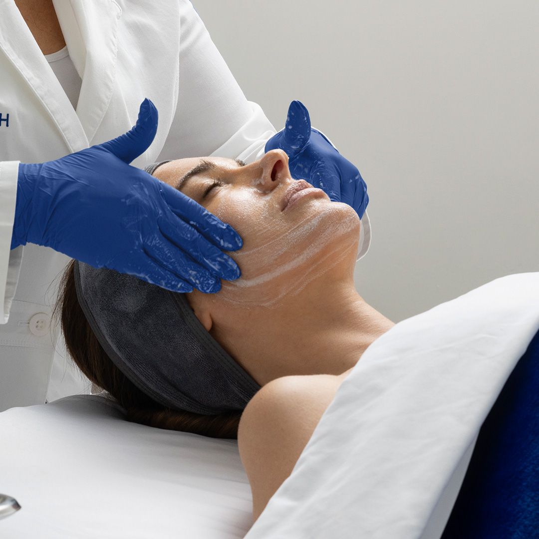 A woman is getting a facial treatment with blue gloves