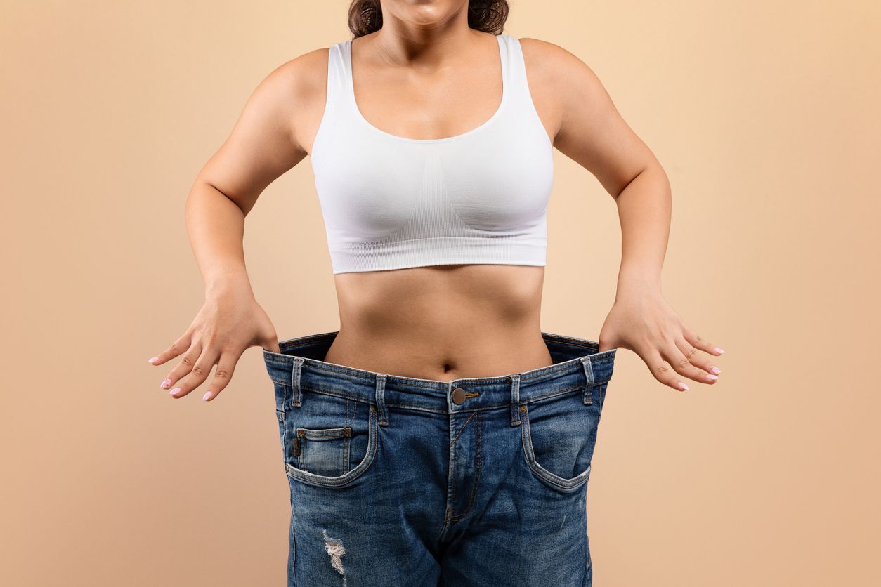 A woman is holding a scale and an apple in her hand.