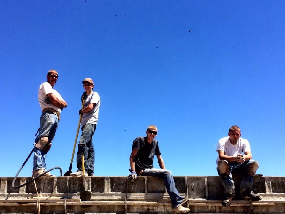 A group of construction workers standing and sitting on a ledge