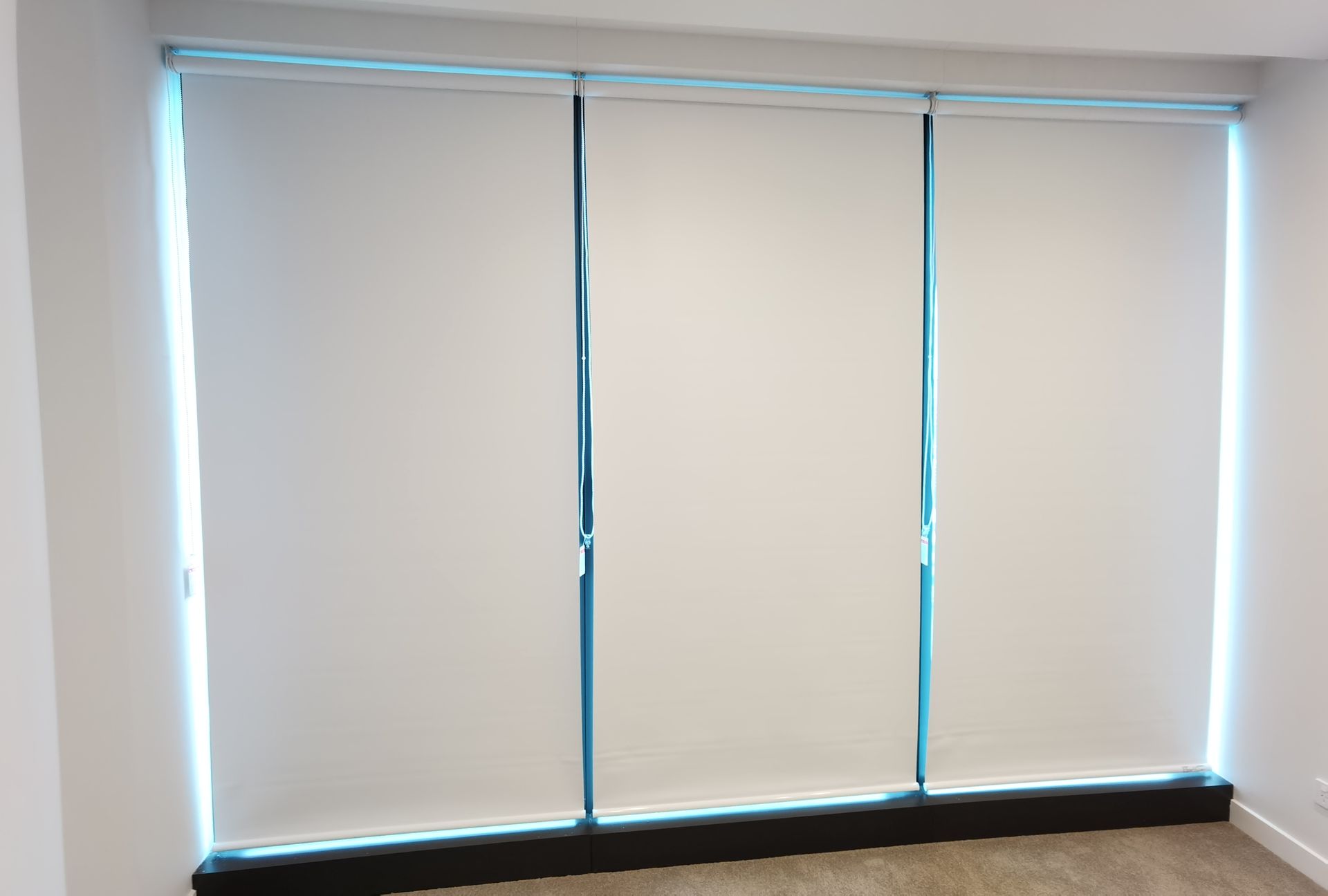 A room with three white blinds on the windows.
