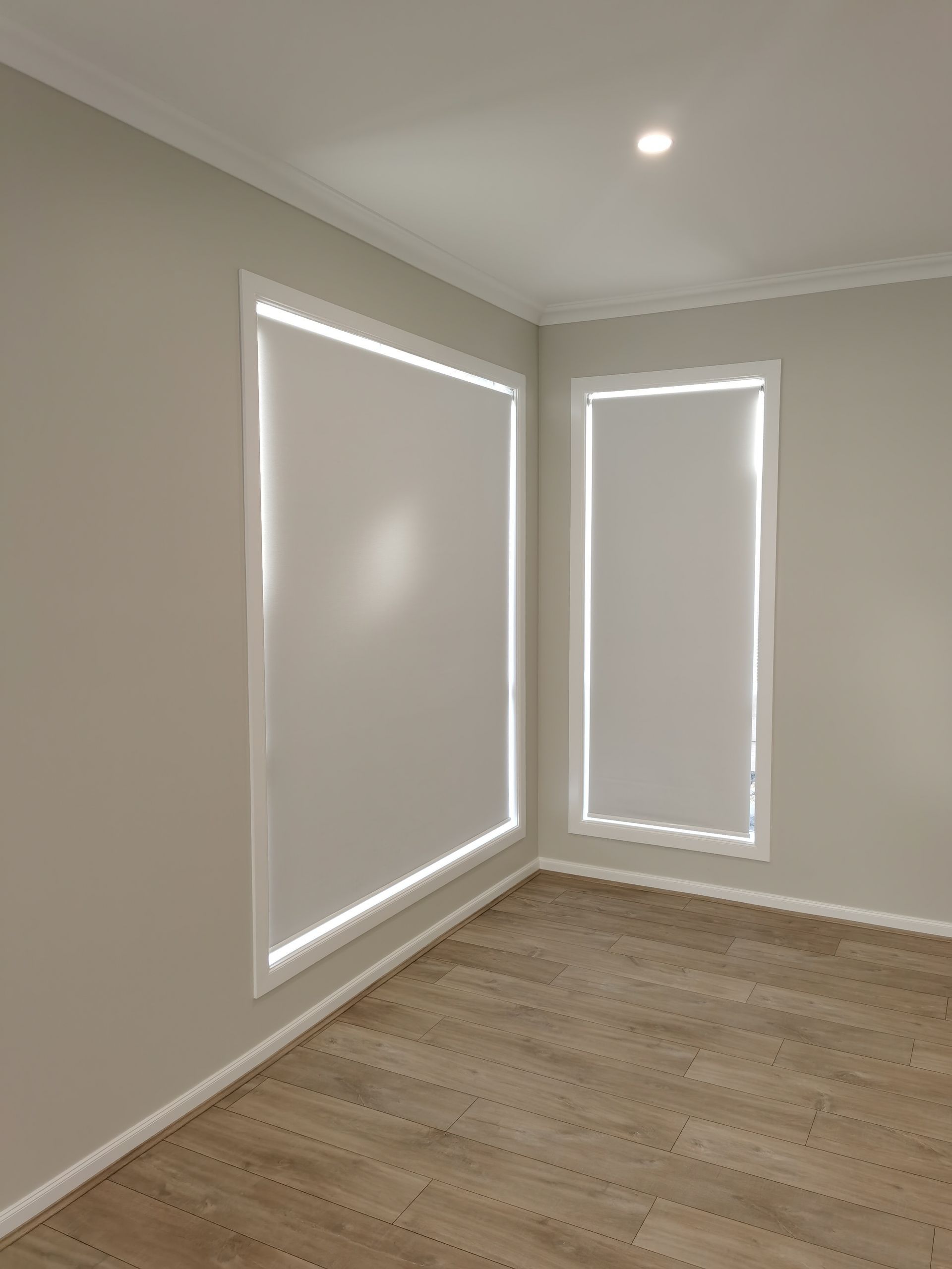 An empty room with two windows and a wooden floor.