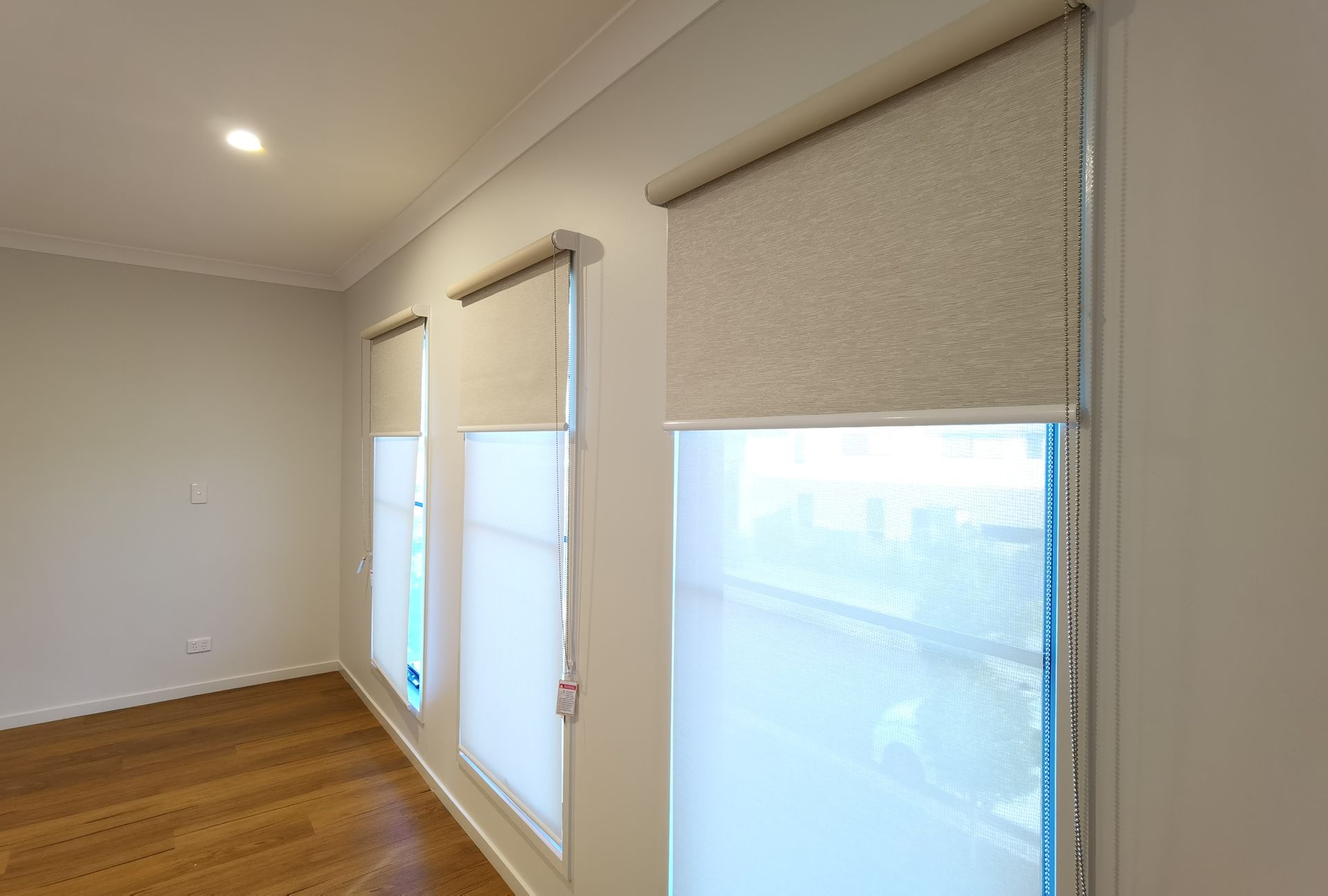 A room with three windows and roller blinds on the windows.