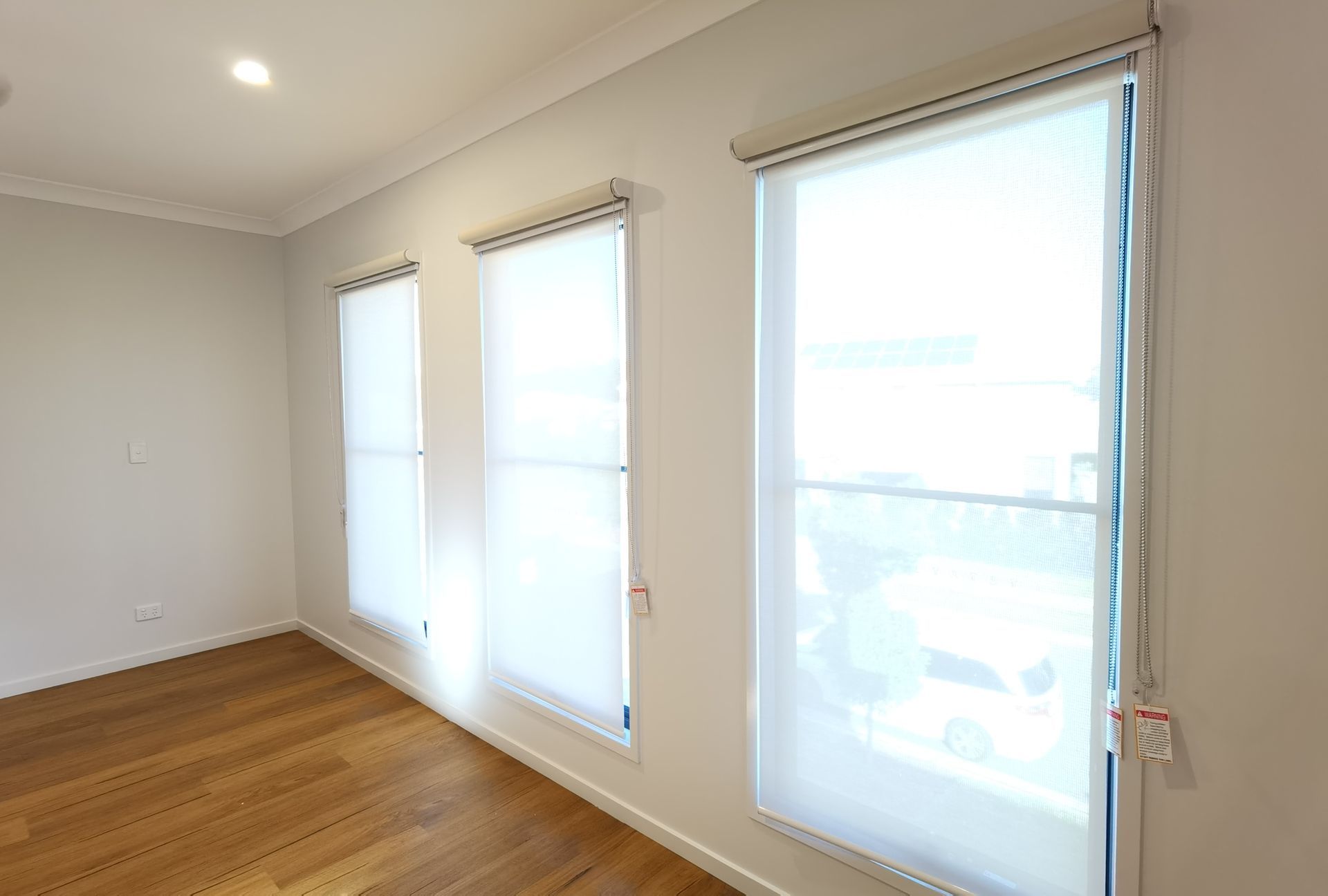 A room with three windows and a wooden floor.