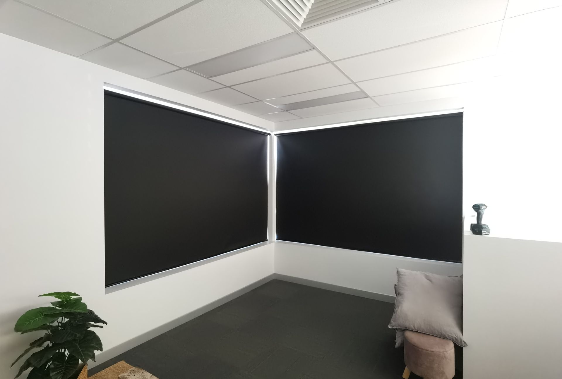 A room with black blinds on the windows and a couch.
