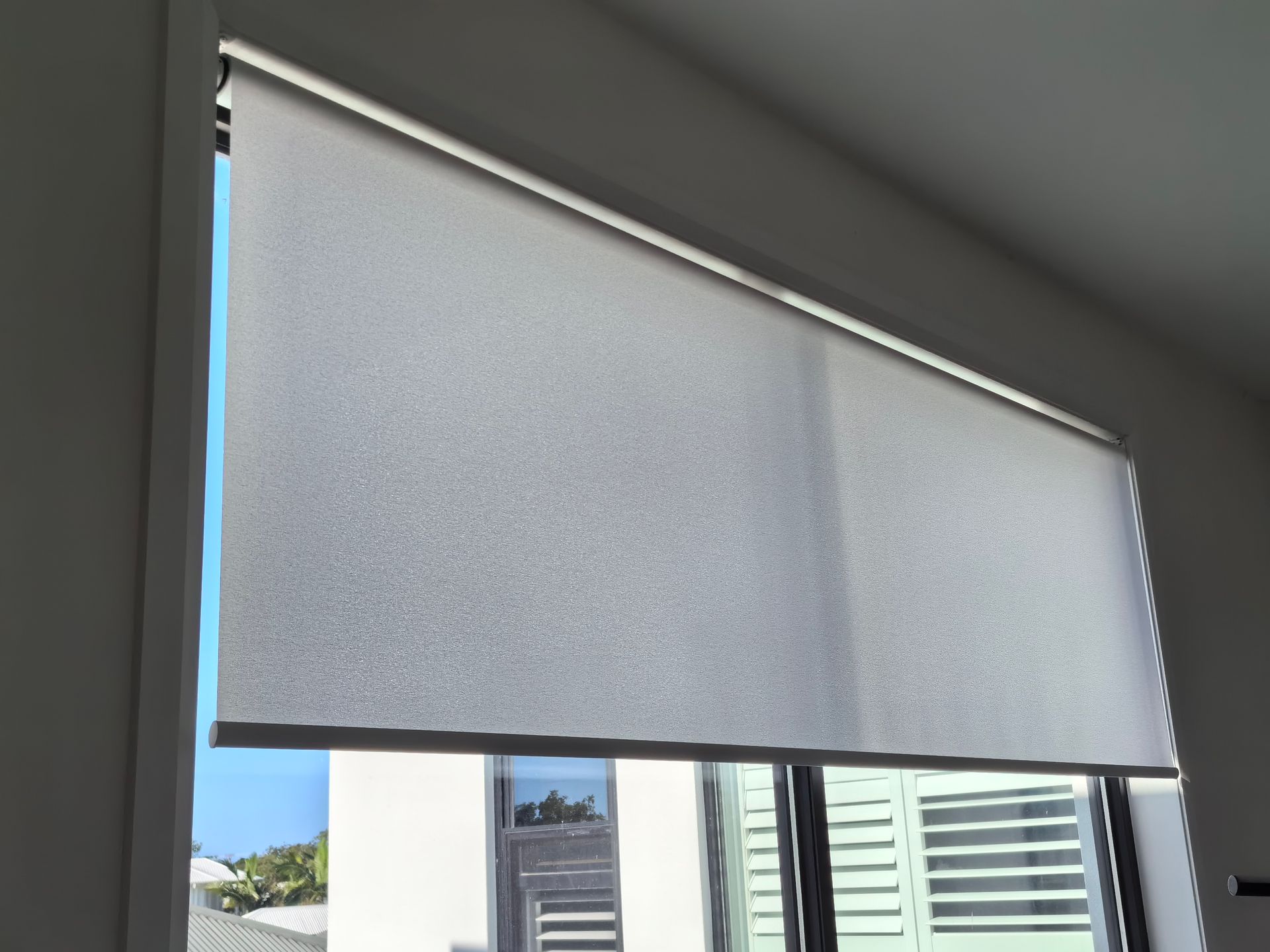 A window with a white roller blind on it