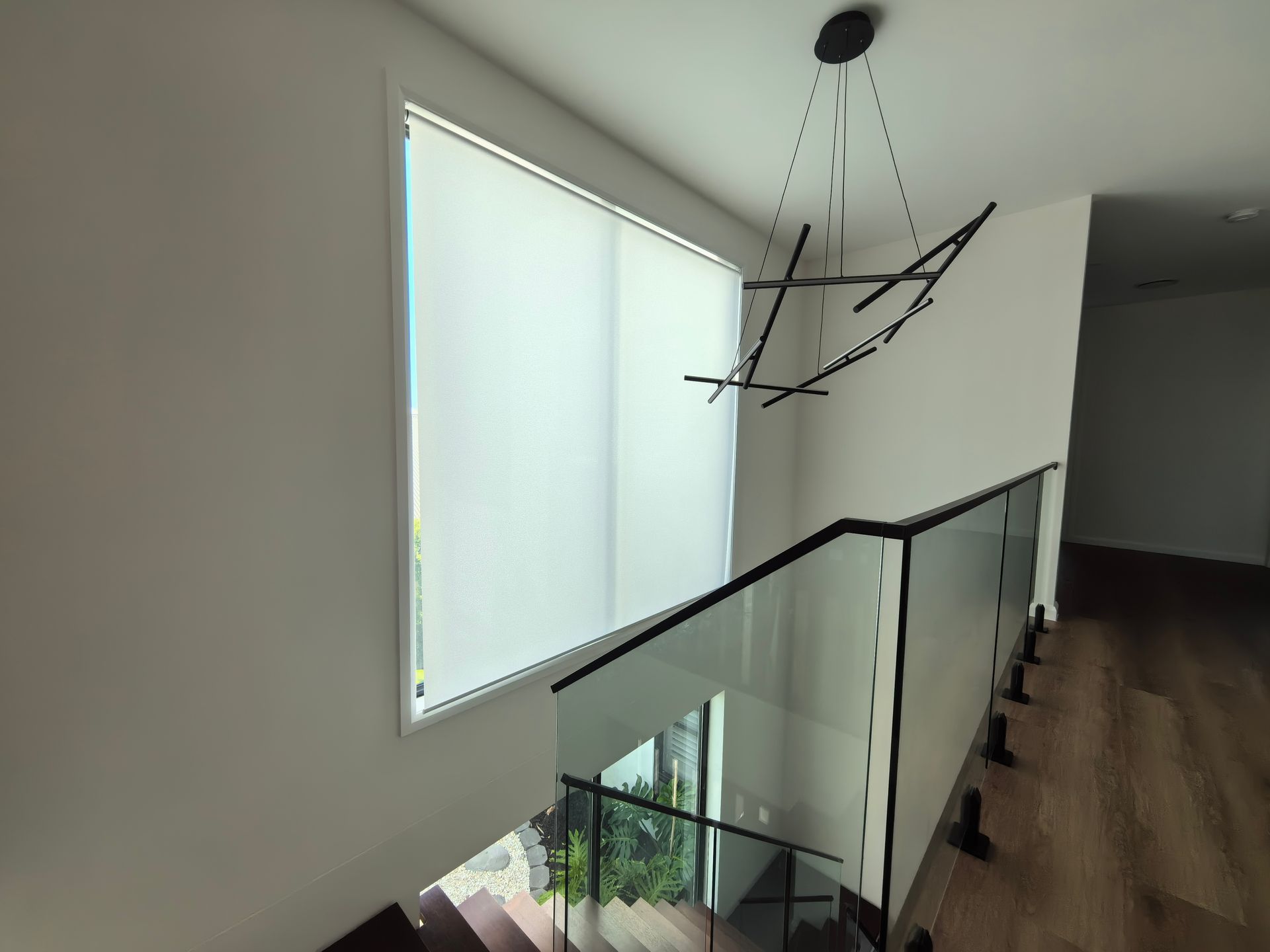 A staircase with a glass railing and a large window.