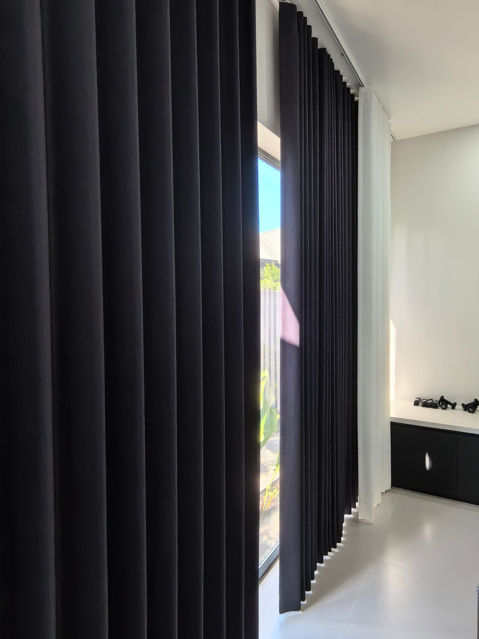 A room with black curtains and a large window.