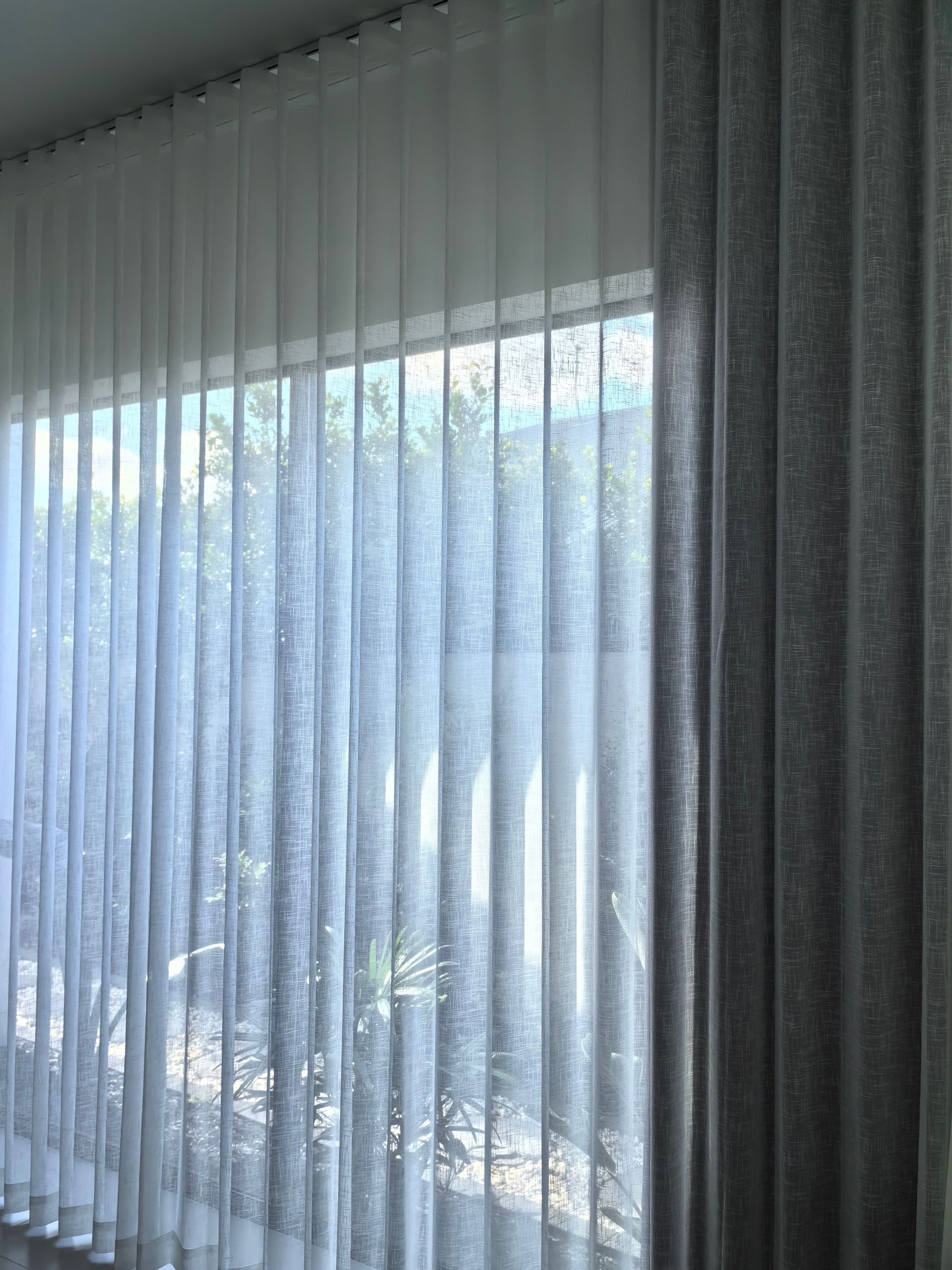 A pair of white curtains are hanging on a window in a room.