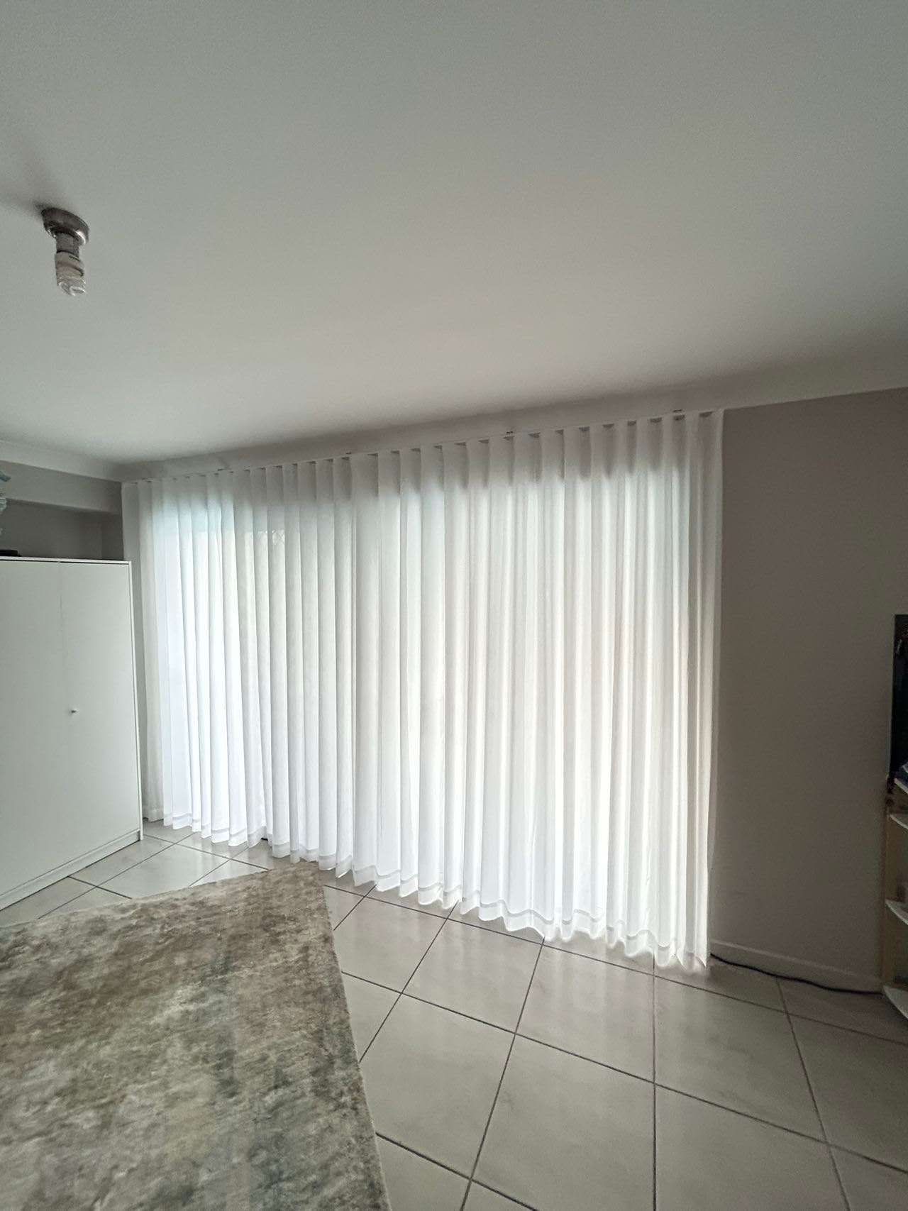 A living room with a sliding glass door and white curtains.