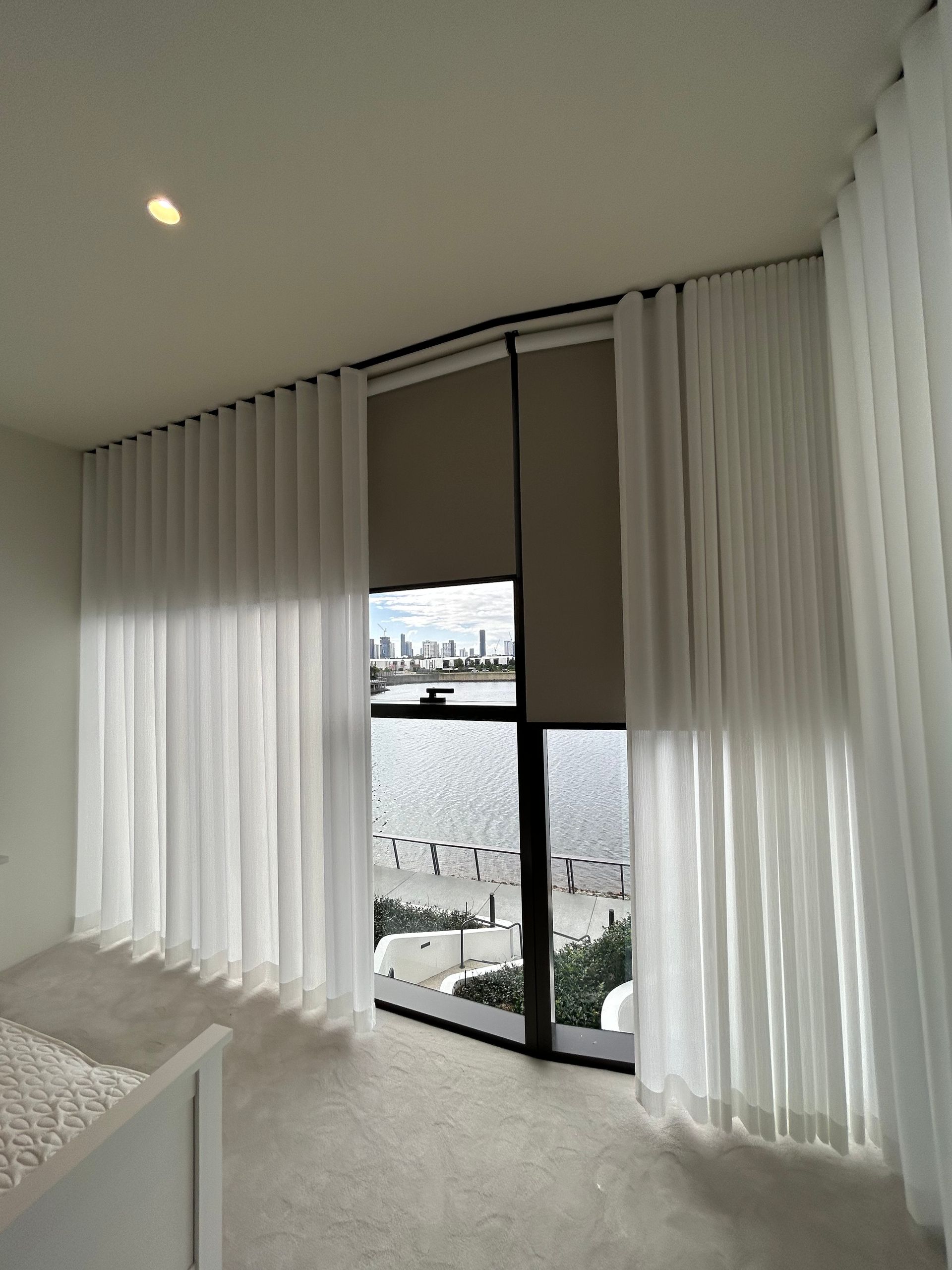 A bedroom with a large window and white curtains