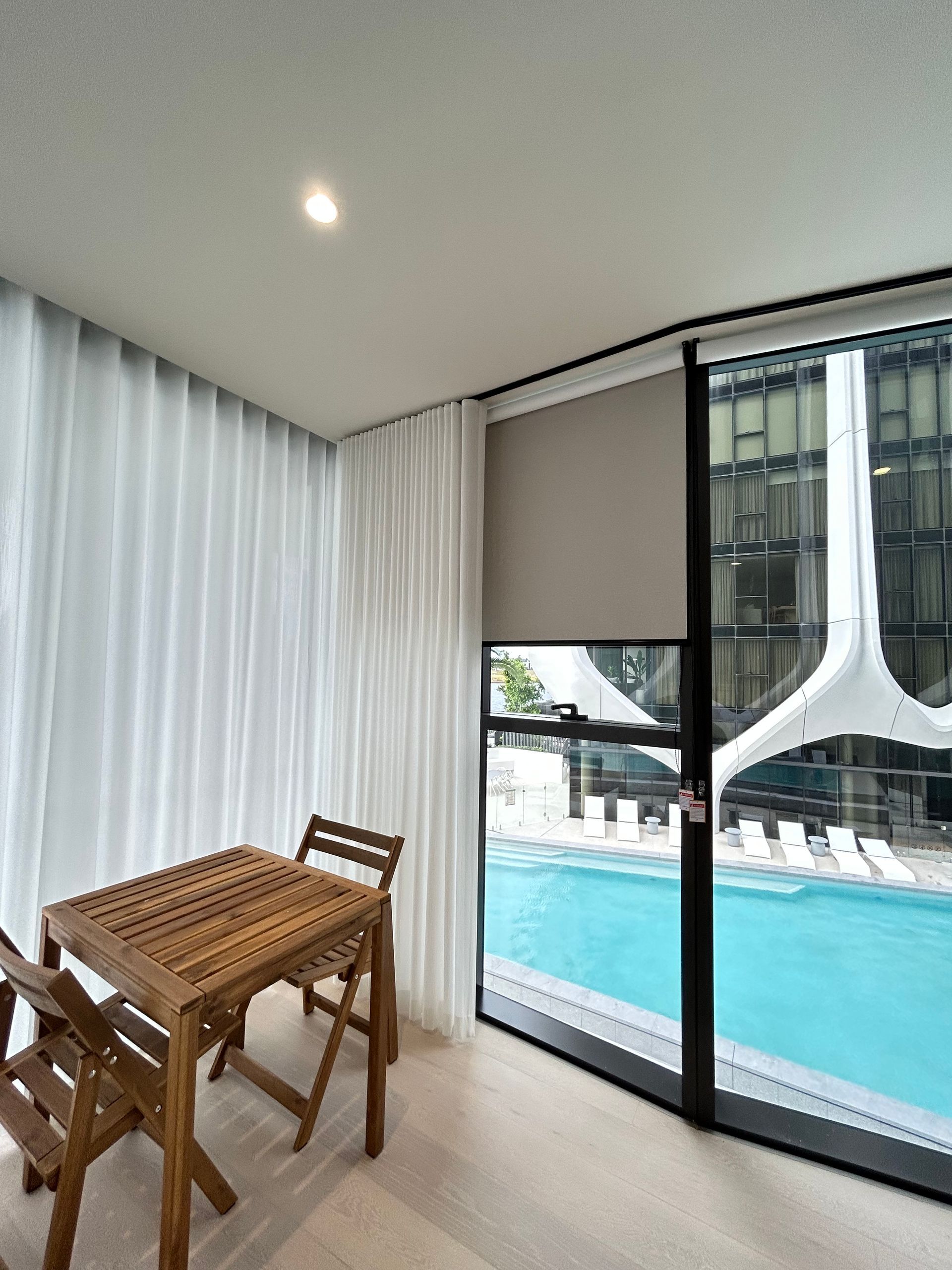 A room with a table and chairs next to a swimming pool
