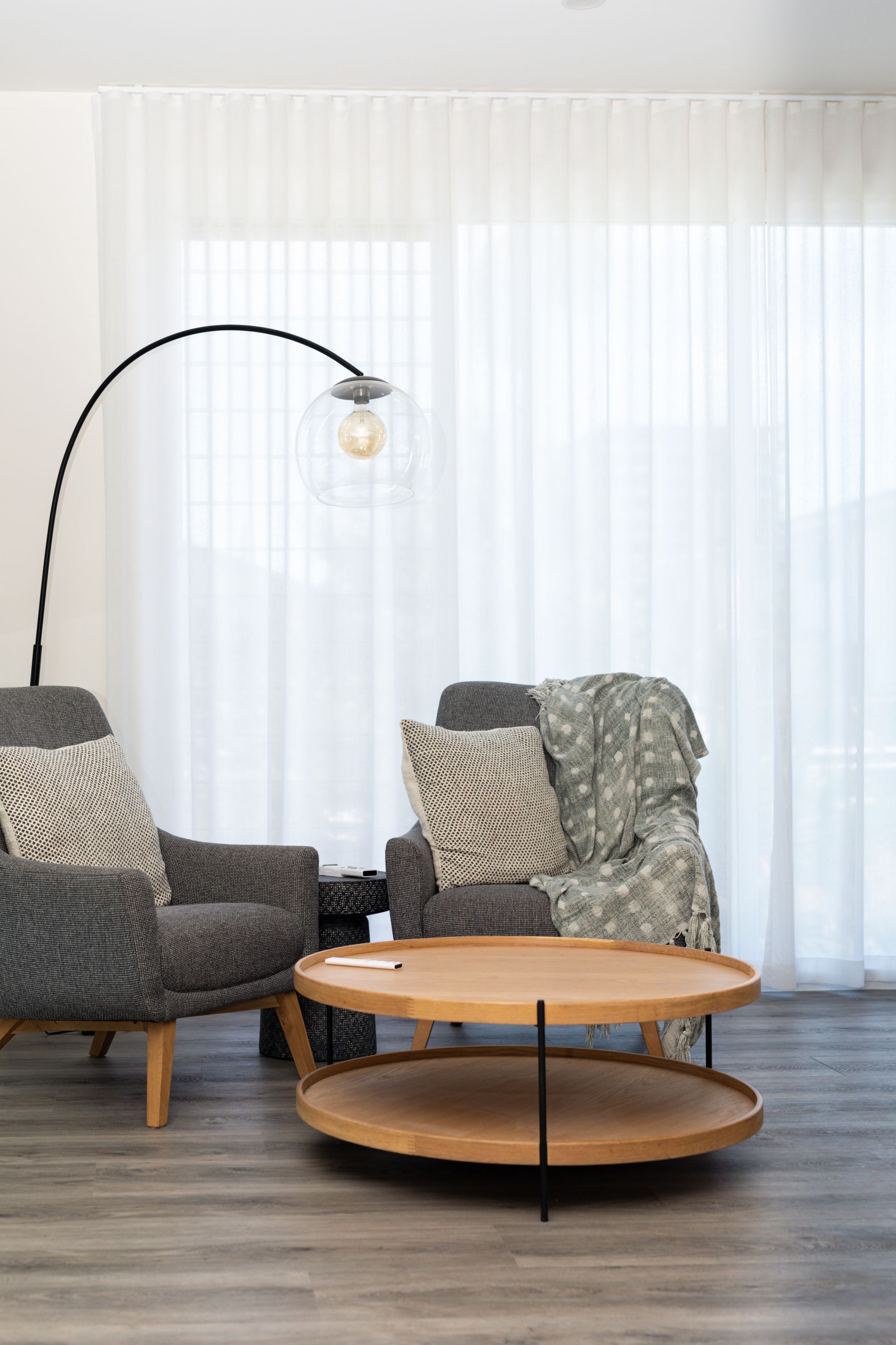 A living room with two chairs , a coffee table , and a lamp.