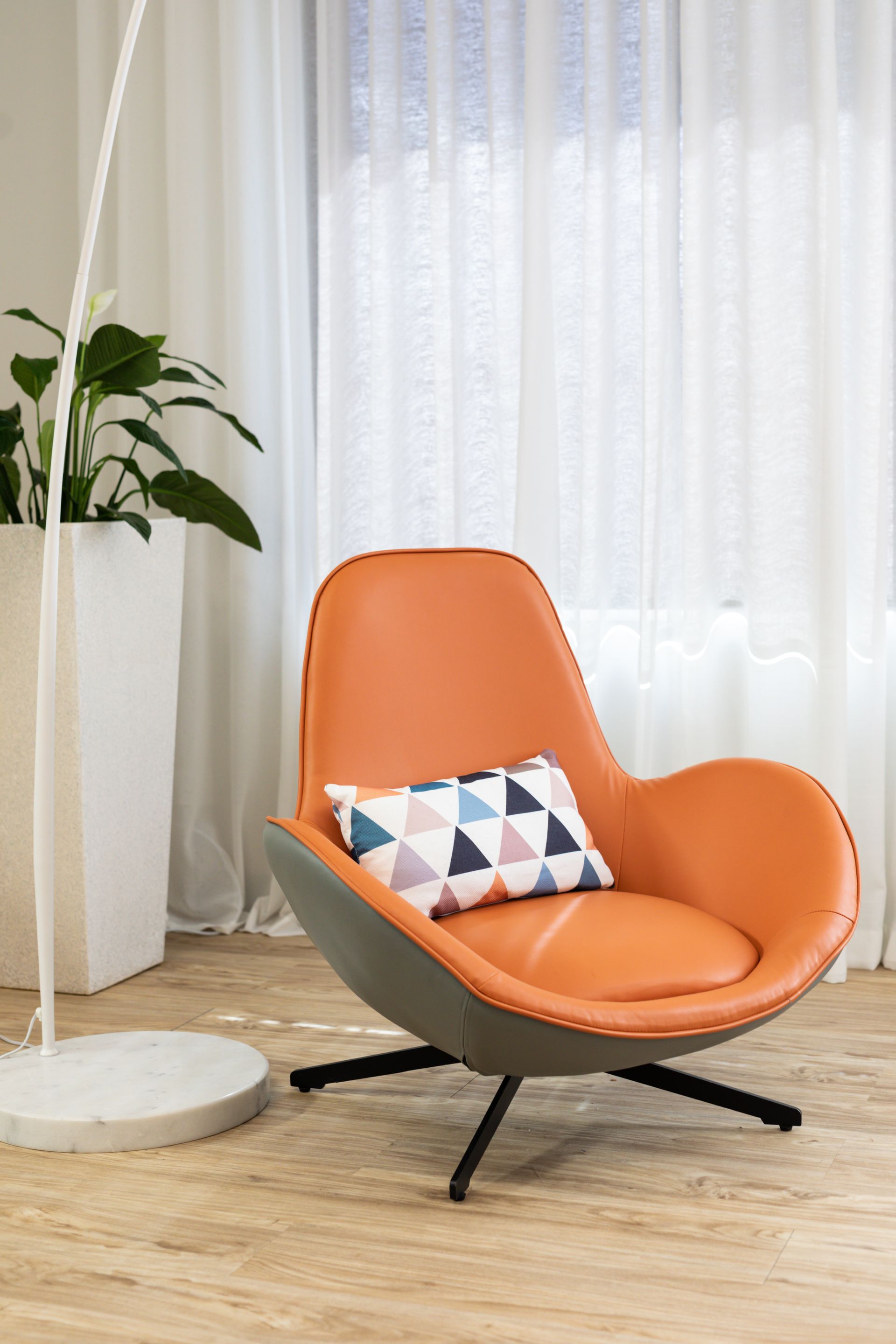 A chair with a pillow on it is sitting in a living room next to a window.