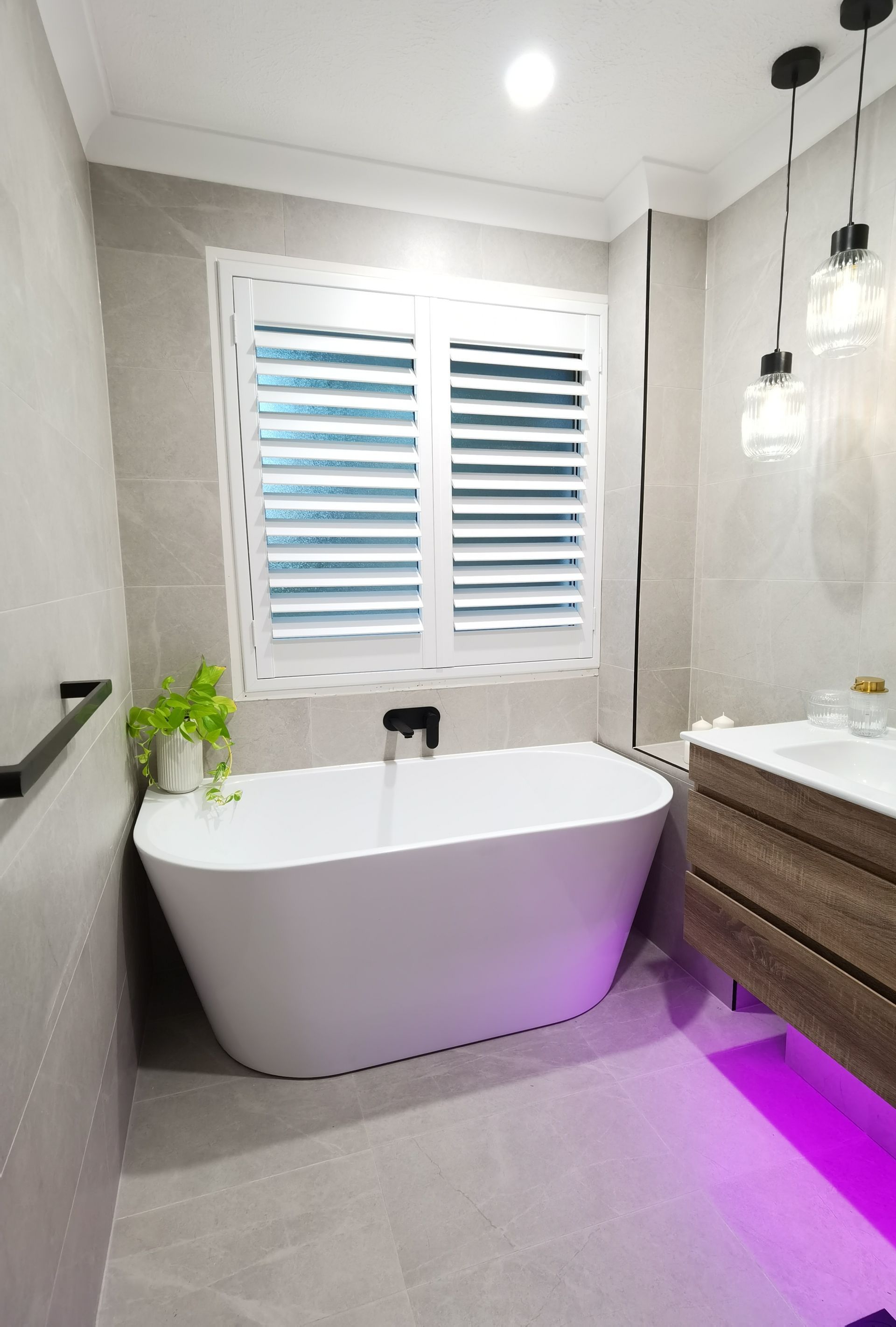 A bathroom with a bathtub , sink , and window.